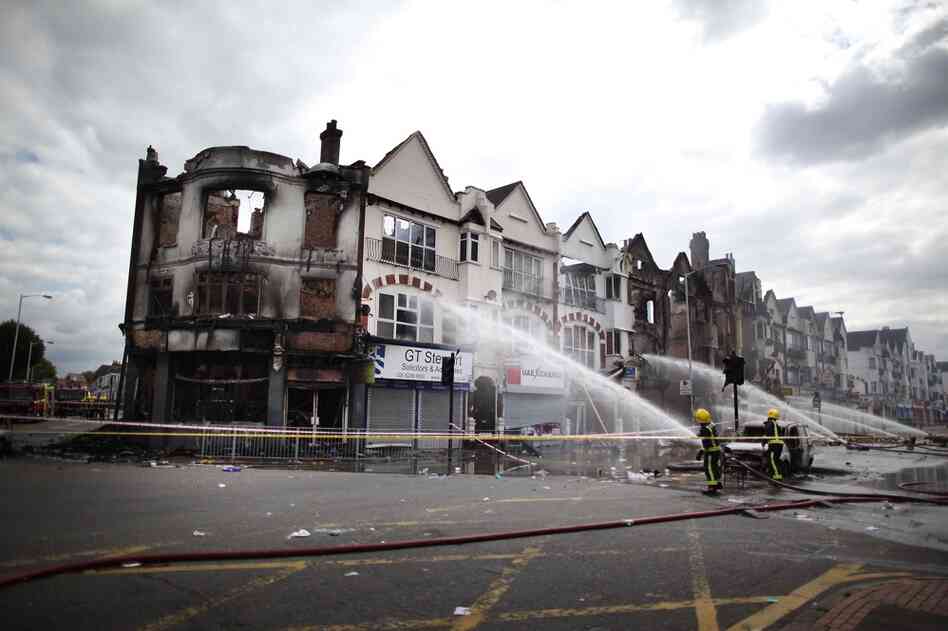 Firefighters damp smoldering buildings in the south London suburb of Croydon on Aug. 9. Emergency services have been cleaning up after three nights of rioting. 
