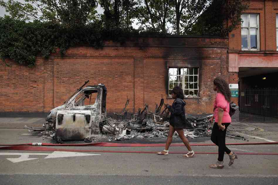 The rioting began in Tottenham after the police shooting that killed Duggan on Aug. 4. Women pass by a burned-out van on Tottenham High Road on Aug. 7. 