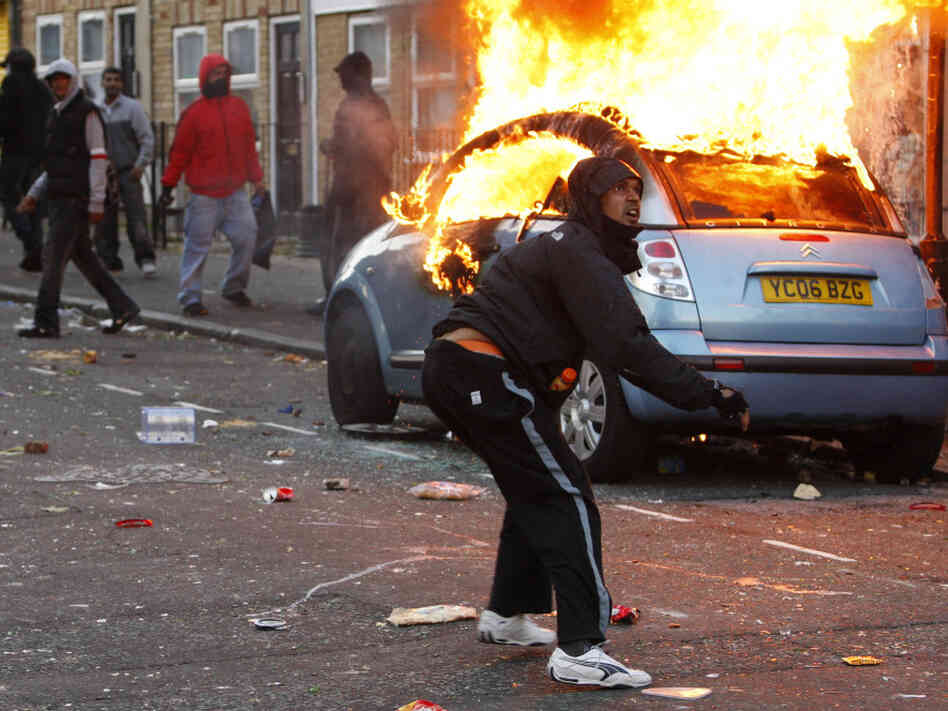 A rioter throws a rock at riot police in Clarence Road in Hackney, London, Monday. The wave of violence has spread to three other major British cities. The riots appeared to have little unifying cause — though some involved claimed to oppose sharp government spending cuts, which will slash welfare payments and cut tens of thousands of public sector jobs through 2015. A rioter throws a rock at riot police in Clarence Road in Hackney, London, Monday. The wave of violence has spread to three other major British cities. The riots appeared to have little unifying cause — though some involved claimed to oppose sharp government spending cuts, which will slash welfare payments and cut tens of thousands of public sector jobs through 2015.