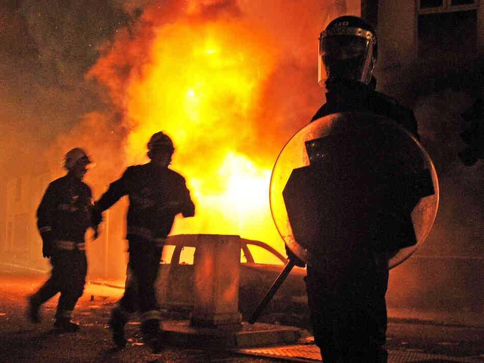 A British riot policeman stands guard in front of a burning building and burnt out car in Croydon, South London on August 8, 2011. A British riot policeman stands guard in front of a burning building and burnt out car in Croydon, South London on August 8, 2011.