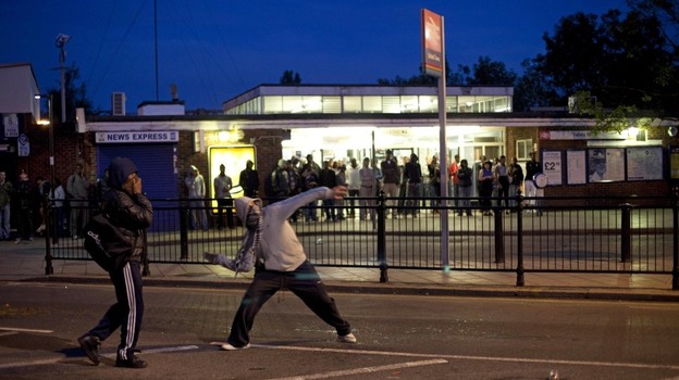 Youths throw bricks at police in this Sunday, Aug. 7, 2011 photo  during unrest in Enfield, north London. Nearly 1,200 people have been arrested since the riots erupted Saturday, mostly poor youths from a broad section of Britain's many races and ethnicities.  Britain is bitterly divided on the reasons behind the riots.