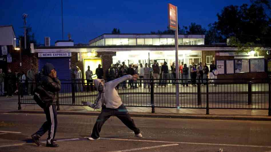 Youths throw bricks at police in this Sunday, Aug. 7, 2011 photo  during unrest in Enfield, north London. Nearly 1,200 people have been arrested since the riots erupted Saturday, mostly poor youths from a broad section of Britain's many races and ethnicities.  Britain is bitterly divided on the reasons behind the riots.