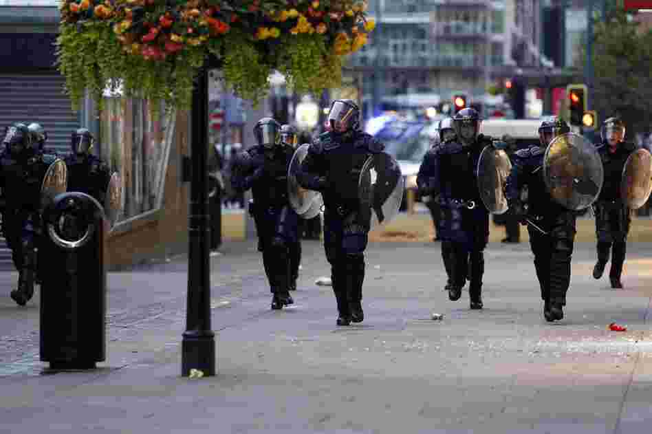 Riot police patrol the street in Manchester on Aug 9. Britain began flooding London's streets with 16,000 police officers, nearly tripling their presence, to combat the worst rioting in a generation. 