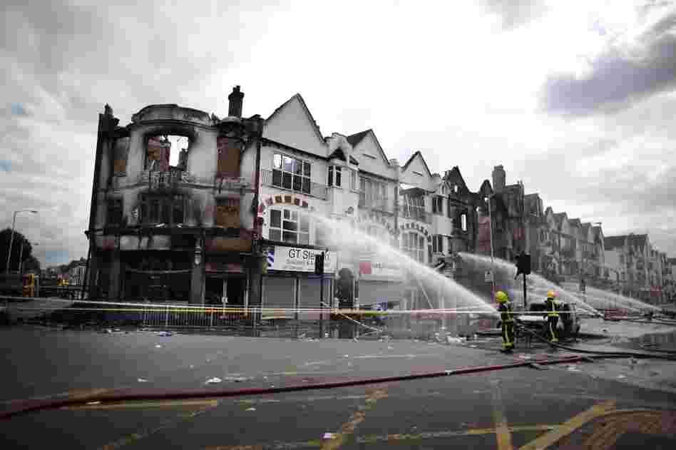 Firefighters damp smoldering buildings in the south London suburb of Croydon on Aug. 9. Emergency services have been cleaning up after three nights of rioting. 