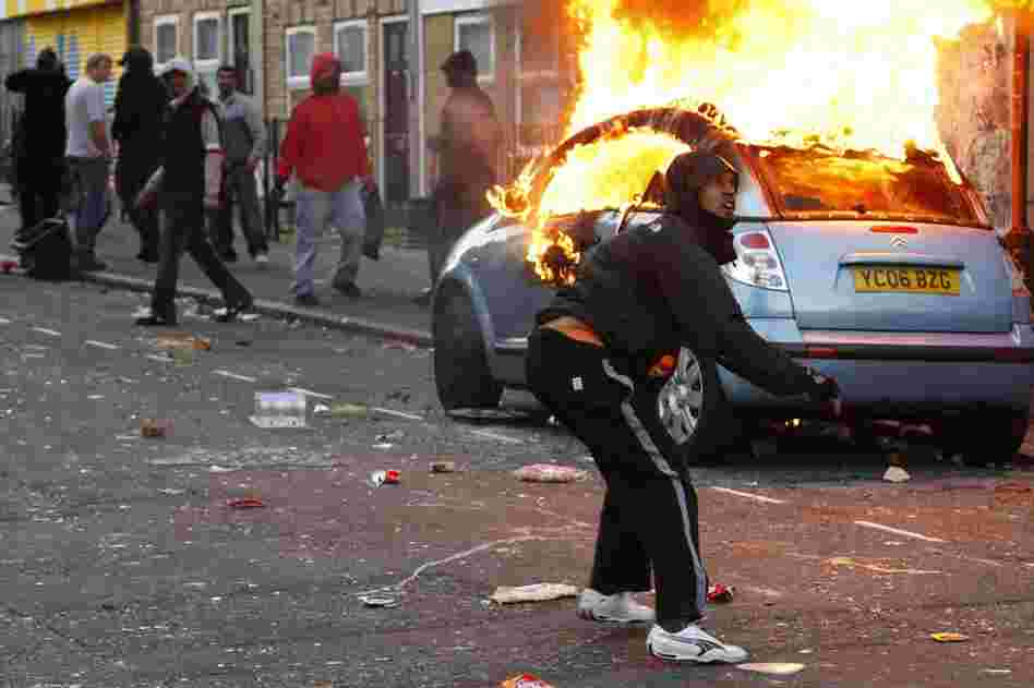 A rioter throws a rock at riot police in Hackney, London, on Aug. 8. 