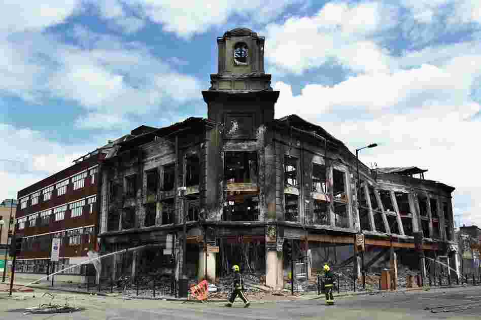 Fireman walk past the smoldering remains of a burned-out building after riots on Tottenham High Road in North London, Aug. 7. 
