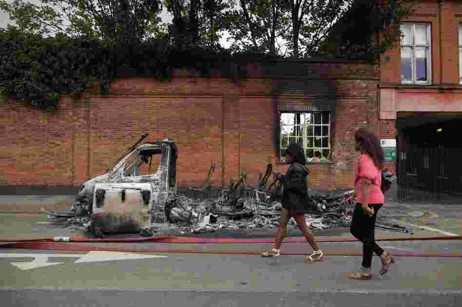 The rioting began in Tottenham after the police shooting that killed Duggan on Aug. 4. Women pass by a burned-out van on Tottenham High Road on Aug. 7. 