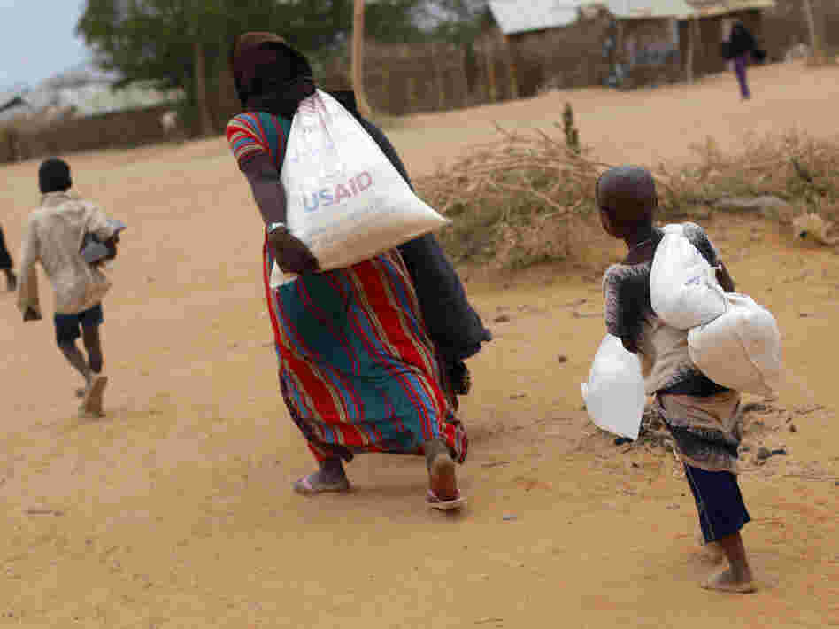 A Somali family carries their supply of food aid as they arrive at a refugee camp outside Dadaab in northeastern Kenya along the Somali border, Aug. 5, 2011. A Somali family carries their supply of food aid as they arrive at a refugee camp outside Dadaab in northeastern Kenya along the Somali border, Aug. 5, 2011.