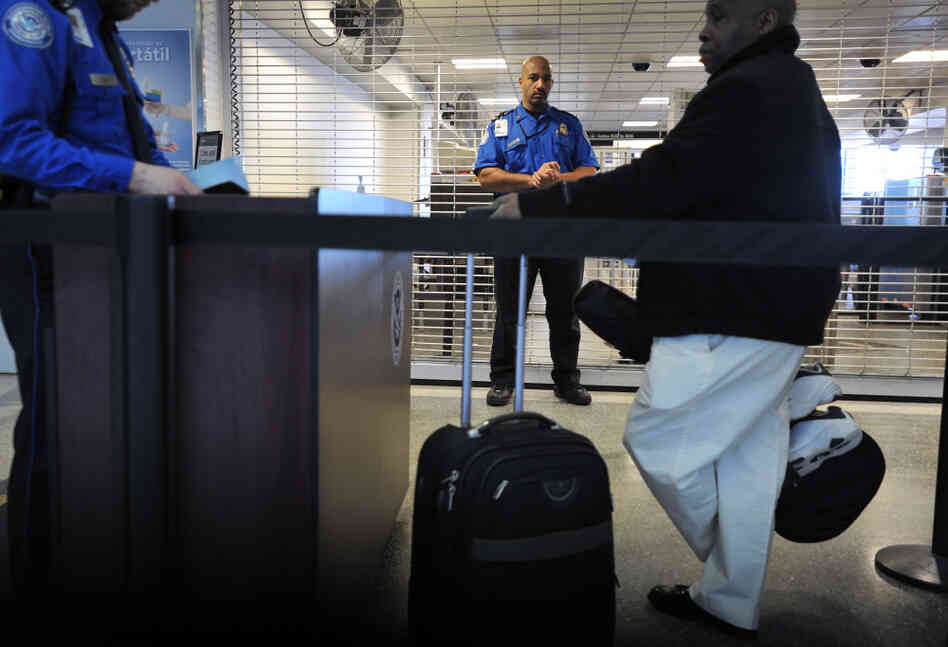 A TSA employee being trained in behavioral pattern recognition watches passengers in line at Boston's Logan International Airport in 2010. This week, Logan will become the first U.S. airport to require every passenger to go through behavioral profiling.