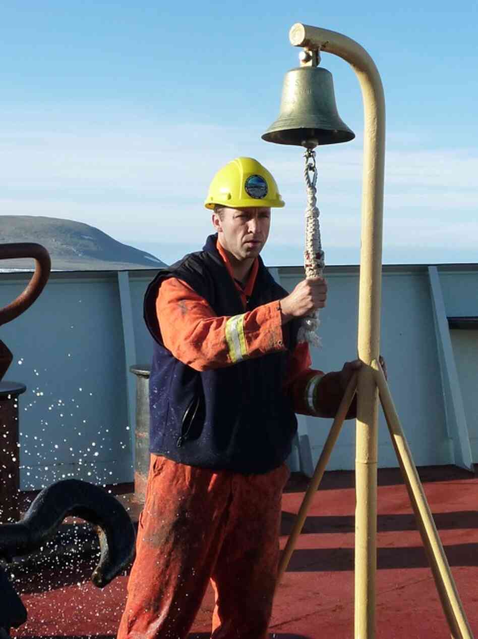 Seaman Bernie Noseworthy, of Newfoundland, provides the traditional signal while the Louis' anchor is raised from the Arctic waters. The bell is rung for each shot of chain — 15 fathoms, or 90 feet — that comes back onboard.