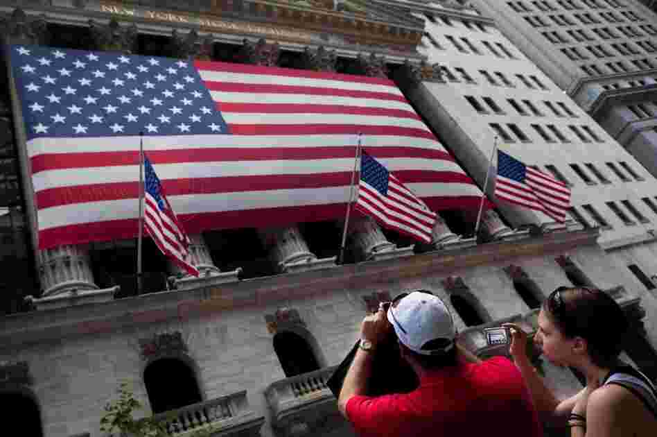 Tourists photograph the New York Stock Exchange building on Wall Street. Of the estimated 60 million 401(k) participants, 87 percent have at least a portion of their portfolio in stocks.