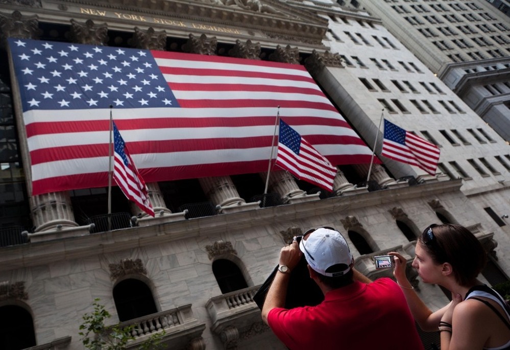 Tourists photograph the New York Stock Exchange building on Wall Street. Of the estimated 60 million 401(k) participants, 87 percent have at least a portion of their portfolio in stocks.