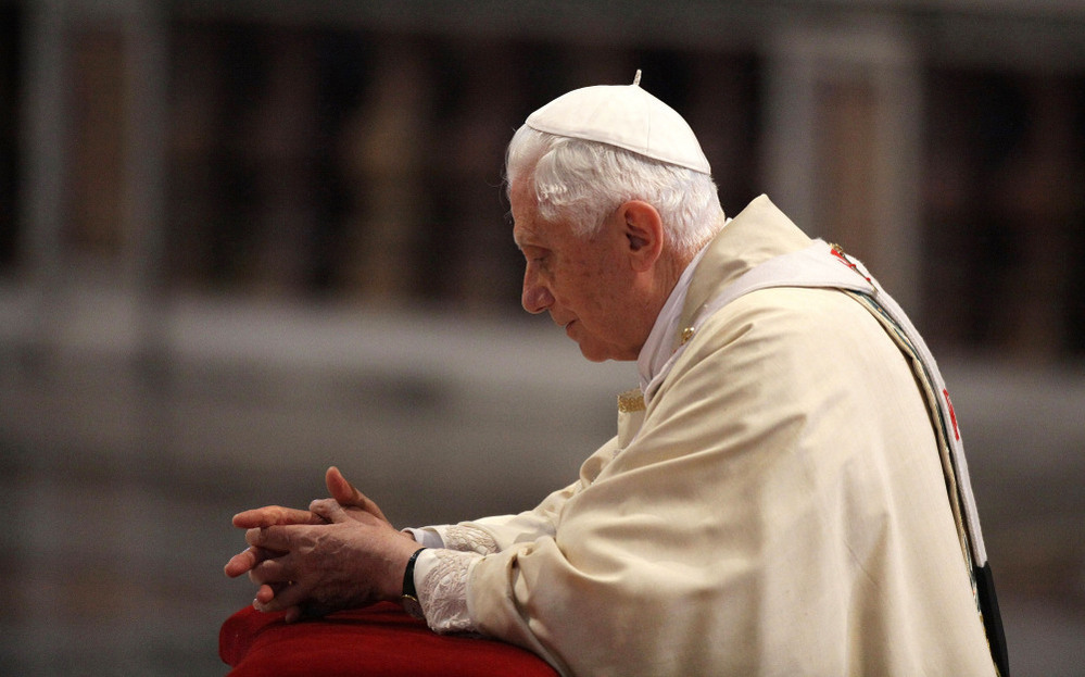 Pope Benedict XVI prays in front of the coffin of his predecessor, John Paul II, at St. Peter's Basilica at the end of a beatification ceremony on May 1, 2011, in Vatican City.