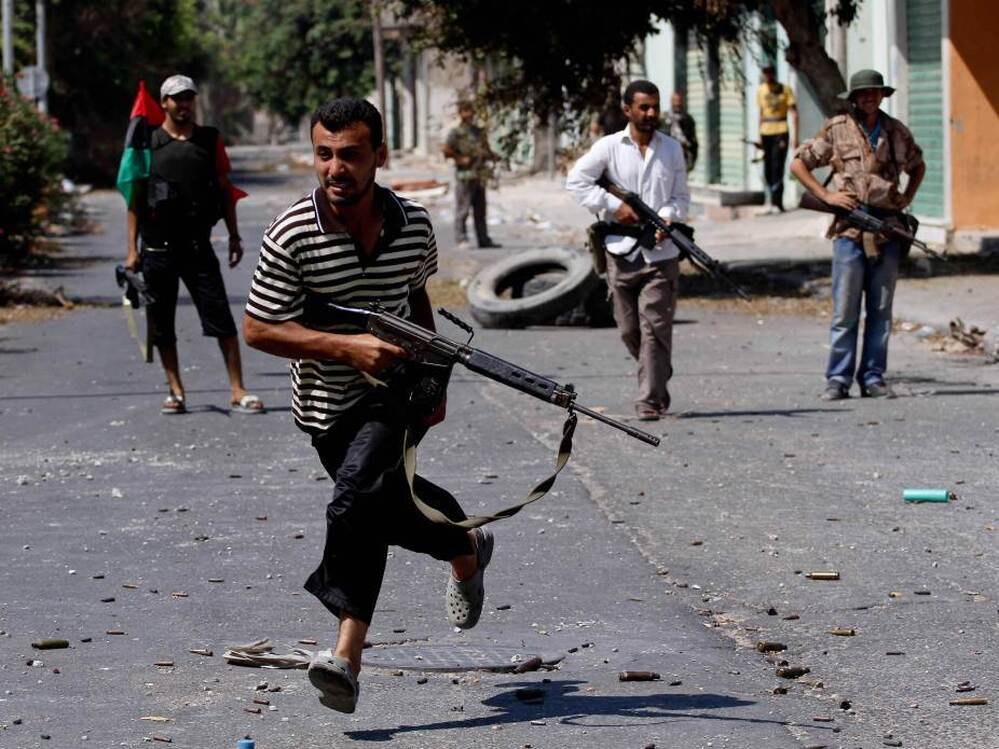 A Libyan rebel dashes over a street to evade sniper fire in Zawiya as rebel forces staged an assault on regime forces in the city's main square Friday.