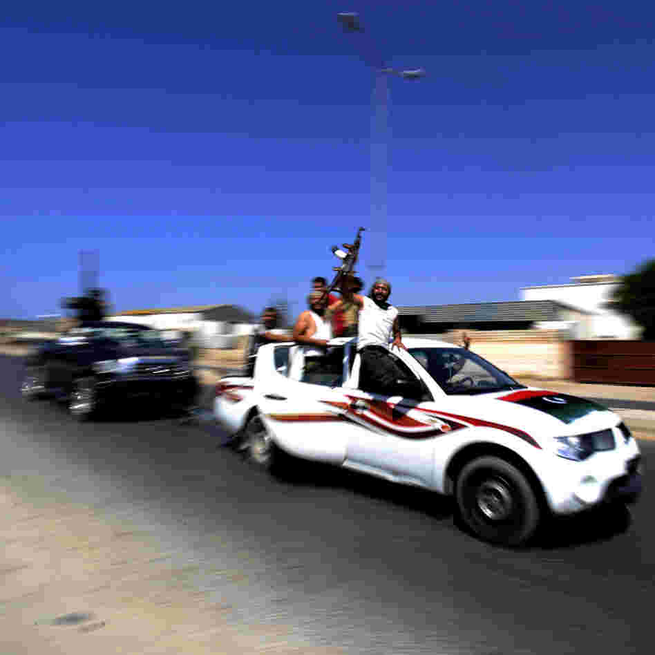 Libyan rebels raise their guns in celebration as they drive through the main road leading to Zawiya. The opposition claimed full control of the strategic city, 30 miles west of Tripoli, on Saturday.