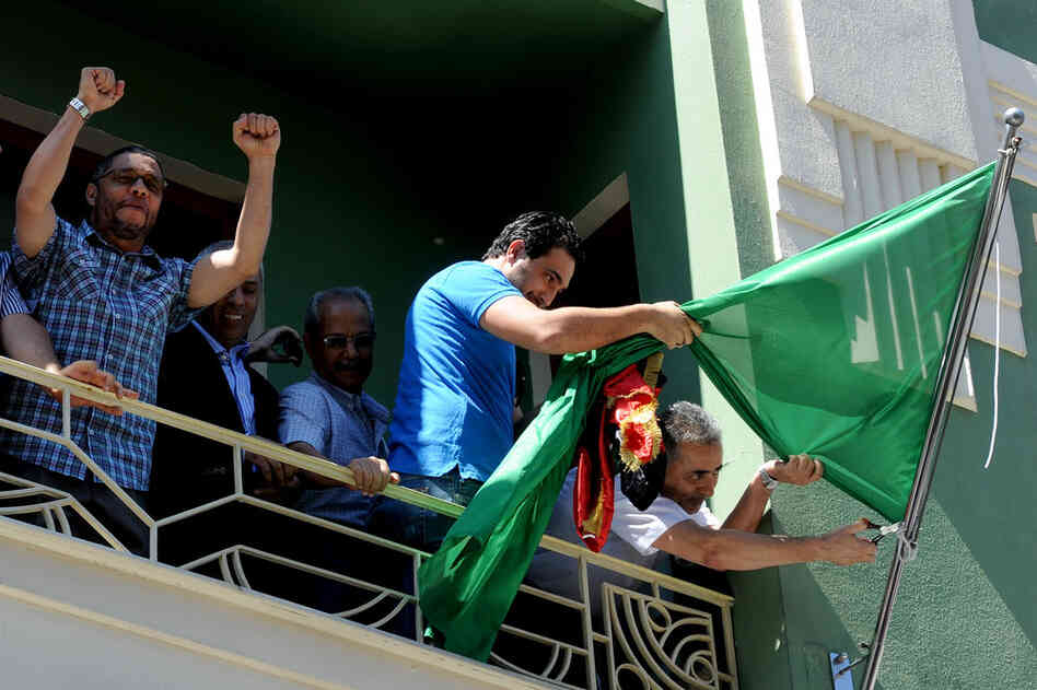 Libyan consul Abdulmacit Ali Said (right) removes the Gadhafi regime flag in Istanbul, Turkey, on Monday. 