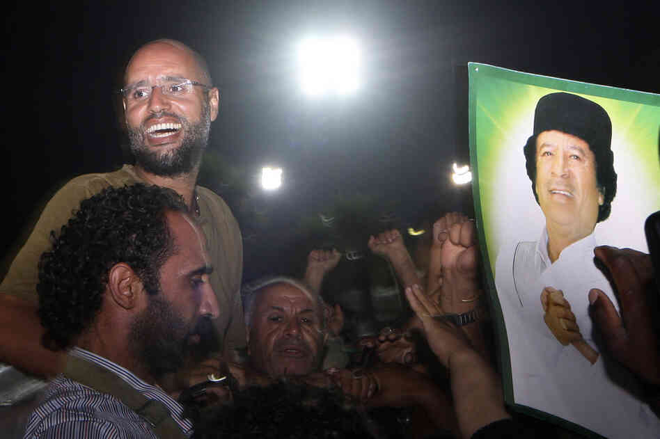 Seif al-Islam Gadhafi (top left) is surrounded by supporters and journalists at his father's residential complex in Tripoli early Tuesday. Fresh fighting erupted in Tripoli hours after his return. 