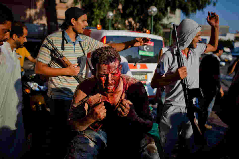 Libyan rebel fighters protect a pro-Gadhafi fighter from angry onlookers as he is brought in for medical attention to the Tripoli Central Hospital following heavy fighting Aug. 25. 