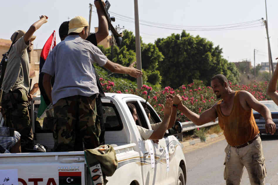 Local residents greet advancing rebel fighters outside Tripoli on Monday. 