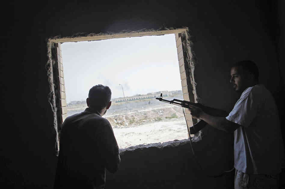 Rebel fighters watch the fighting near Gadhafi's compound Tuesday. 