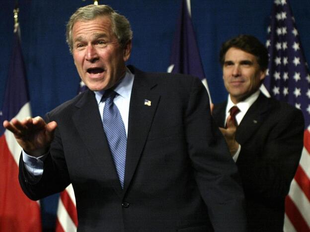 Then President George W. Bush waves as he takes the stage during a Bush-Cheney 2004 reception with Texas Governor Rick Perry at the Hilton Americas  in March 2004 in Houston, Texas. Perry is now considered a front runner for the 2012 GOP presidential nomination.