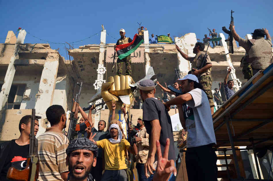 Rebels celebrate around the iconic statue of a golden fist crushing a U.S. military bomber in Tripoli on Wednesday. 
