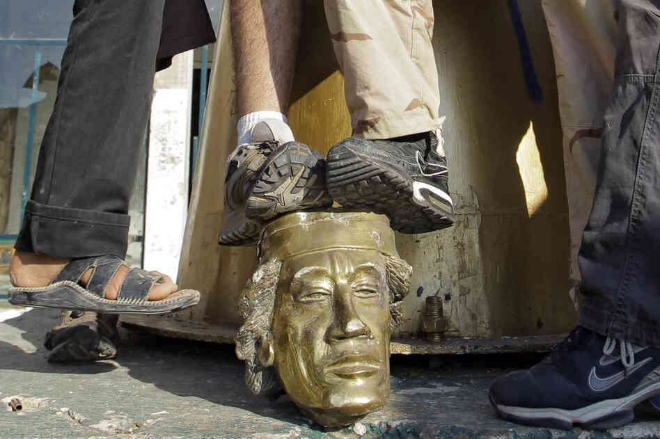 Rebel fighters trample the head of a Gadhafi statue in his compound. 