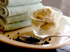 A bowl of Black Pepper Ice Cream on a platter with a spoonful of peppercorns and folded linens A bowl of Black Pepper Ice Cream on a platter with a spoonful of peppercorns and folded linens