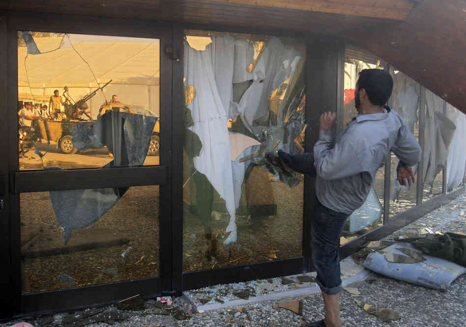 A Libyan rebel breaks the glass of Gadhafi's main compound in Tripoli.  