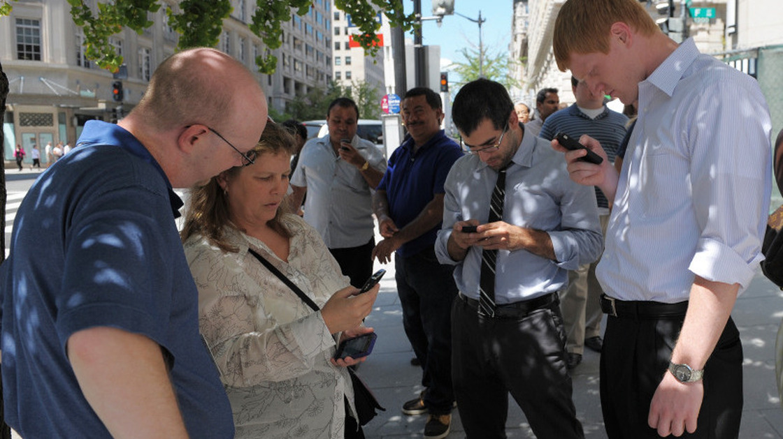 People check their smartphones while standing in the street shortly after an earthquake struck Washington on Tuesday.
