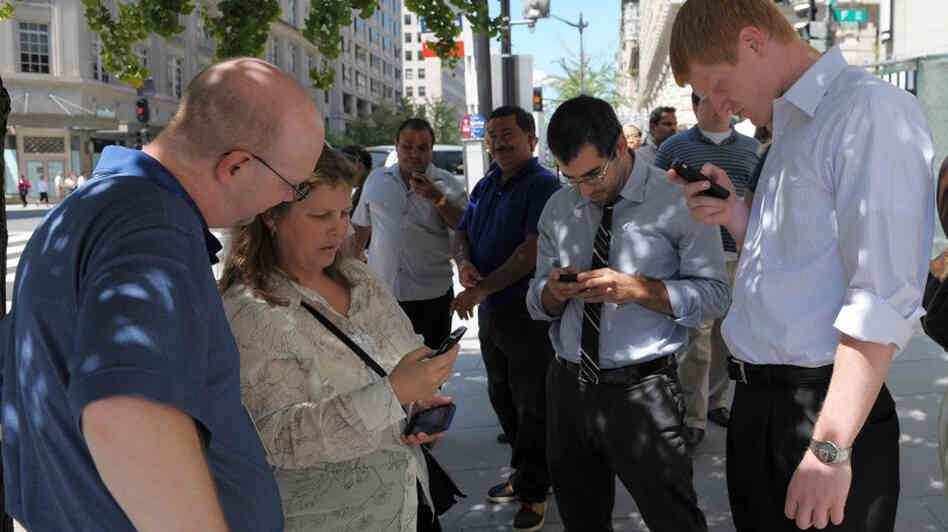 People check their smartphones while standing in the street shortly after an earthquake struck Washington on Tuesday.