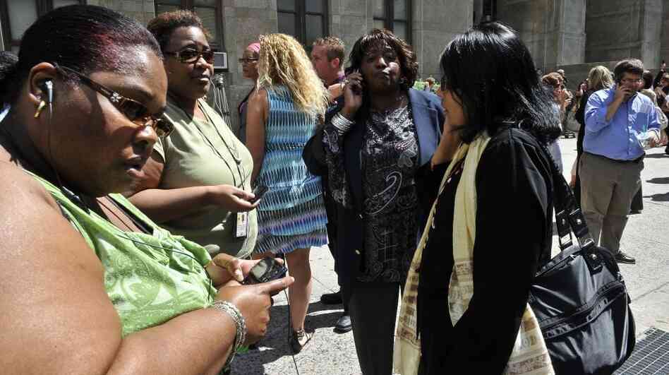 People reach for their cellphones outside the courthouse in Manhattan after an earthquake rattled the East Coast on Tuesday.