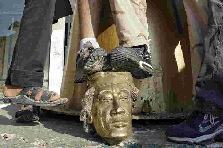 Rebel fighters trample the head of a Gadhafi statue in his compound. 