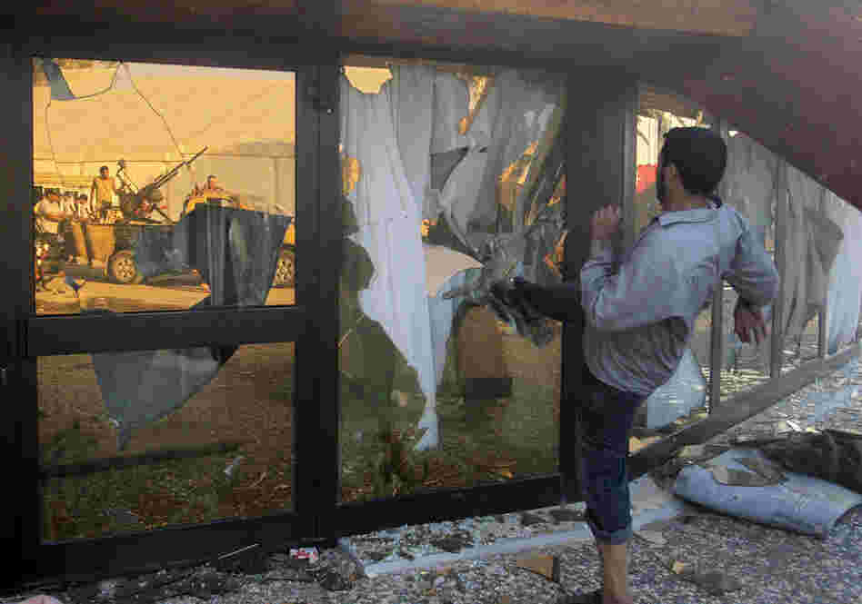 A Libyan rebel breaks the glass of Gadhafi's main compound in Tripoli.  