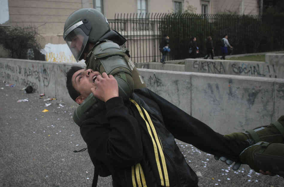 Riot police detain a demonstrator on the second day of a national strike in Santiago, Chile on Thursday.