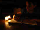 A woman writes in a journal by candlelight. A woman writes in a journal by candlelight.