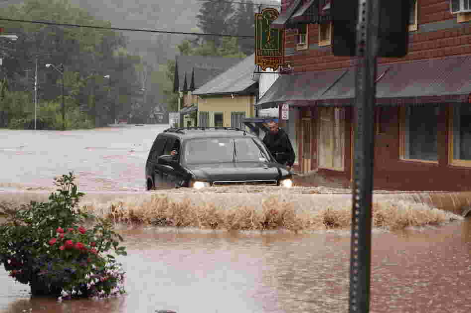 A security guard hangs on the door of Gov. Andrew Cuomo's SUV in the middle of a flooded street Sunday in Margaretville, N.Y. 