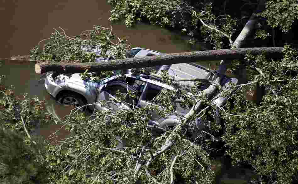A vehicle is covered by trees on a flooded roadway in Southern Shores, N.C., on Sunday after the hurricane swept through the area. 