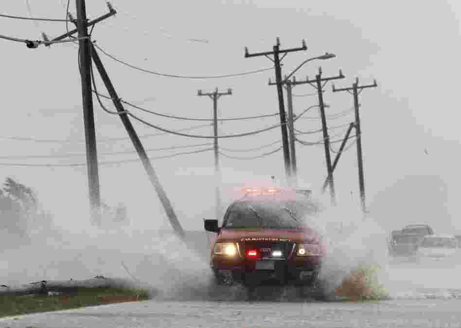 An Oak Bluffs, Mass., fire department vehicle drives through strong winds and ocean spray from the tropical storm while driving along a costal road in Edgartown on Martha's Vineyard on Sunday. 