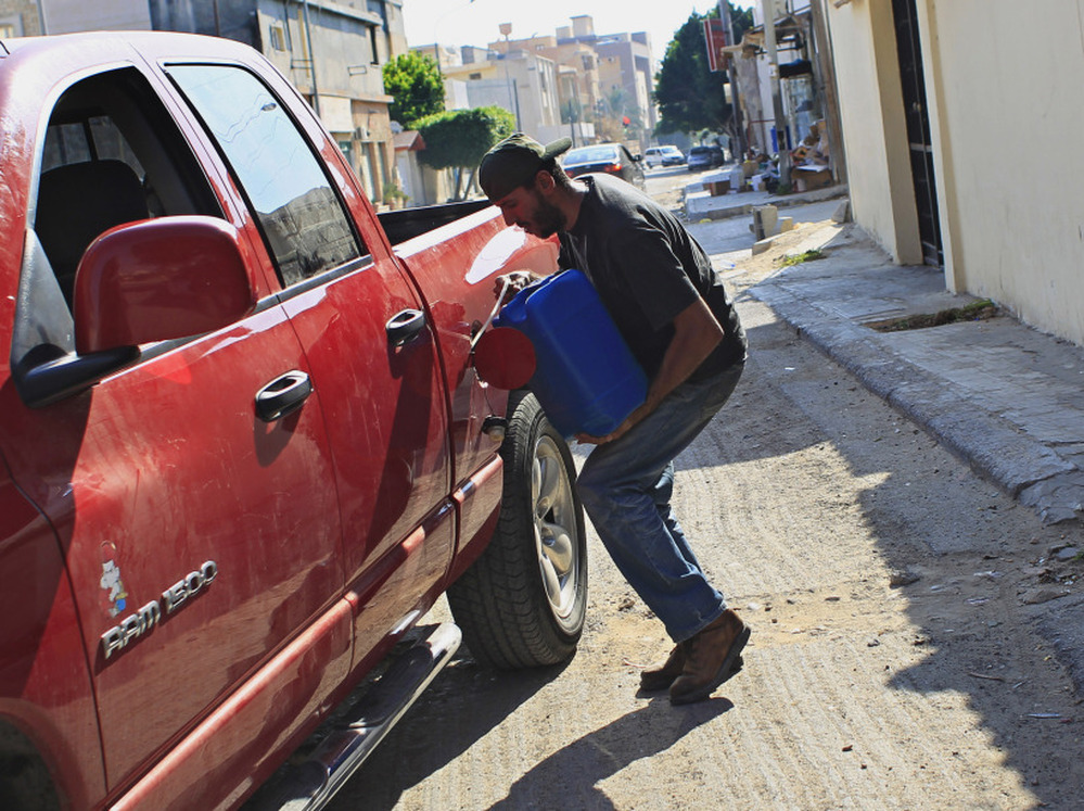 A man pours gas into the tank of his car in Tripoli on Saturday. Residents in the Libyan capital are scrambling to get basic supplies, such as fuel and water.