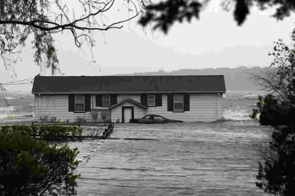 Waves crash around a home Sunday morning in Southampton, N.Y.  