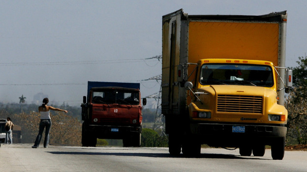 A woman hitchhikes on a highway outside Havana.