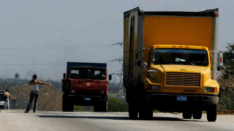 A woman hitchhikes on a highway outside Havana.