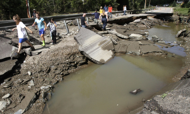 People walk along a washed out section of Route 12 on Monday in Berlin, Vt.