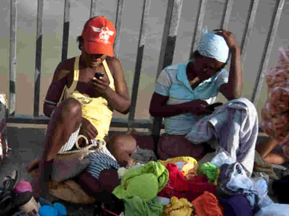 Two women check their cellphones as they hawk their wares on a bridge over the Artibonite River, whose waters are  believed to be the source of Haiti's 2010 cholera outbreak.