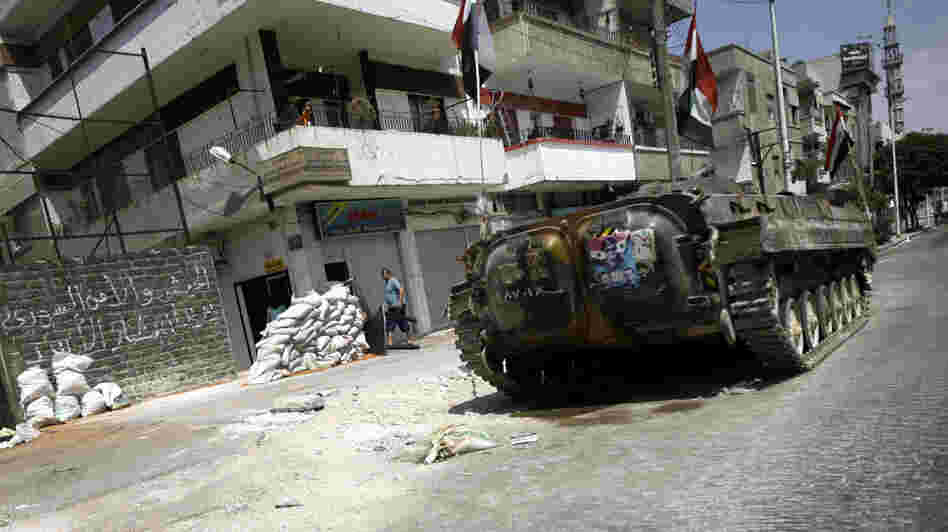 A Syrian military tank takes position in a residential street in the central city of Homs Monday. Government troops reportedly are defecting to join the activists.
