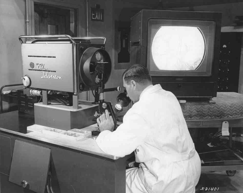 A Walter Reed researcher uses a color TV microscope developed by the center with RCA in 1957. The system allowed the researcher to broadcast slide images across the campus that could be used in a number of classrooms to teach students. 