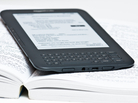 An electronic reader lying on an open paper book. An electronic reader lying on an open paper book.