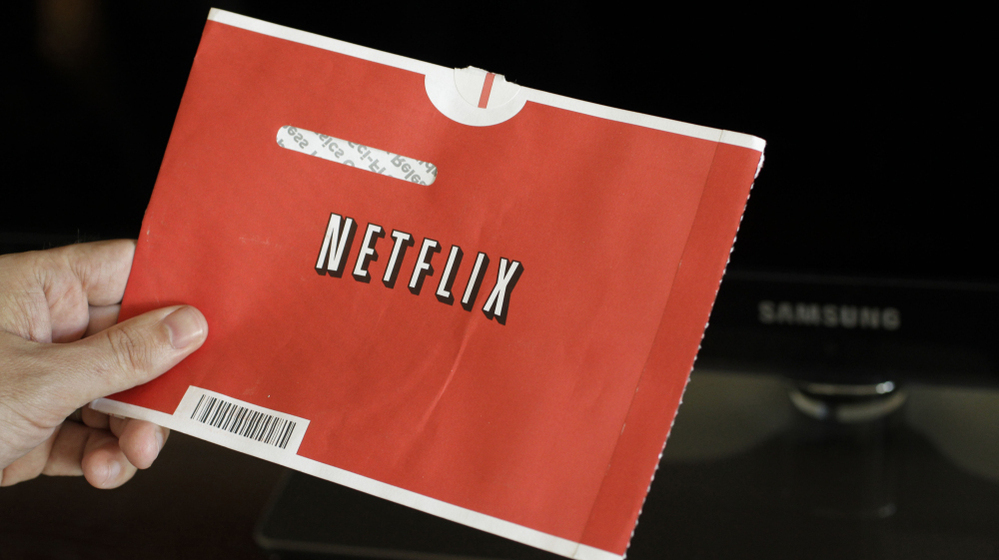 A Netflix customer holds up a movie envelope.