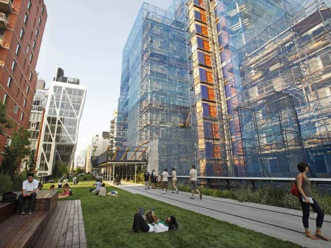 Pedestrians stroll down a walkway as others relax on a stretch of lawn after the second section of the High Line, an industrial era elevated railway line converted into a city park, opened to the public one day early in New York, Tuesday, June 7, 2011.  (AP Photo/Kathy Willens)